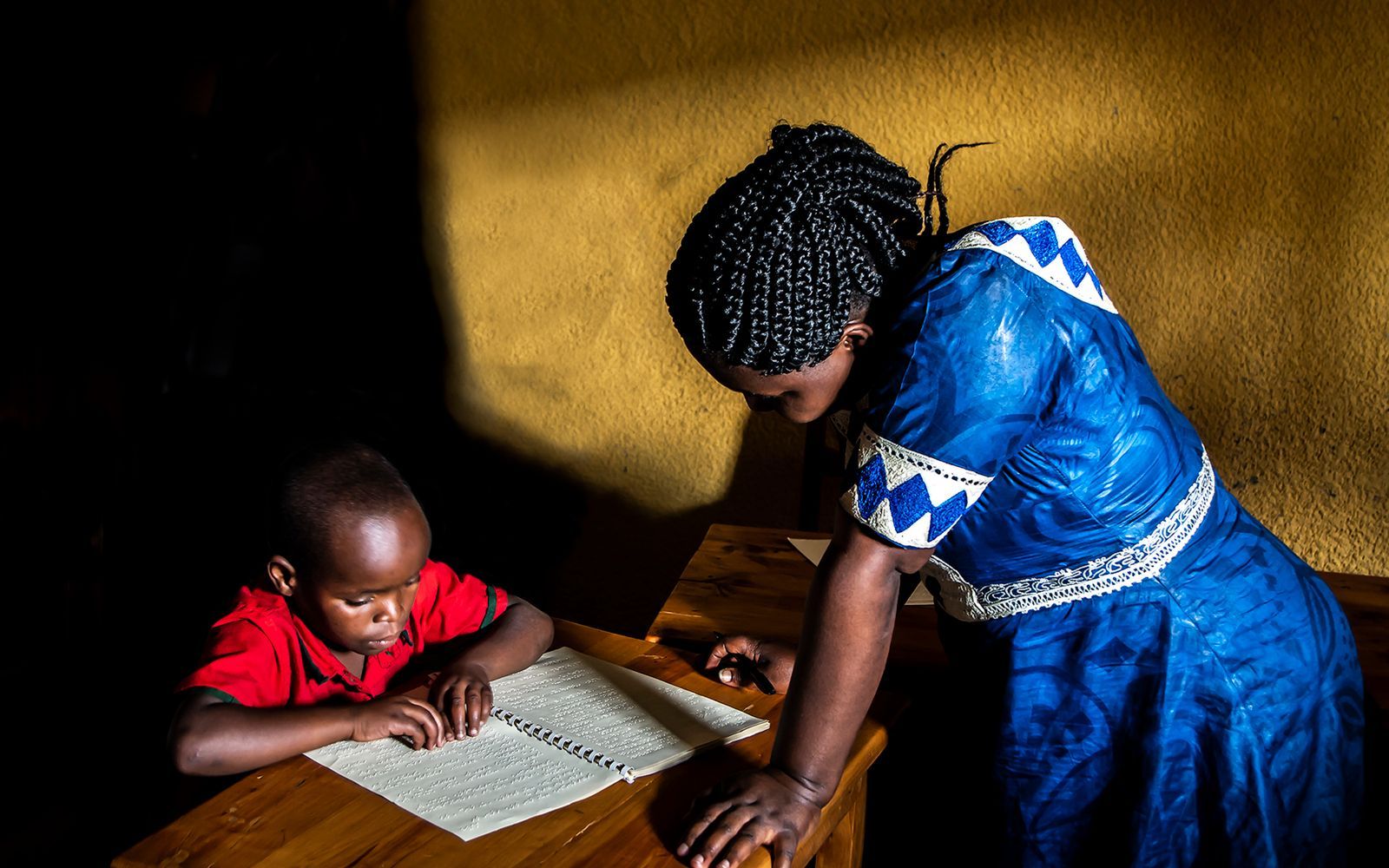 Enseignante accompagnant un jeune enfant dans son travail de lecture